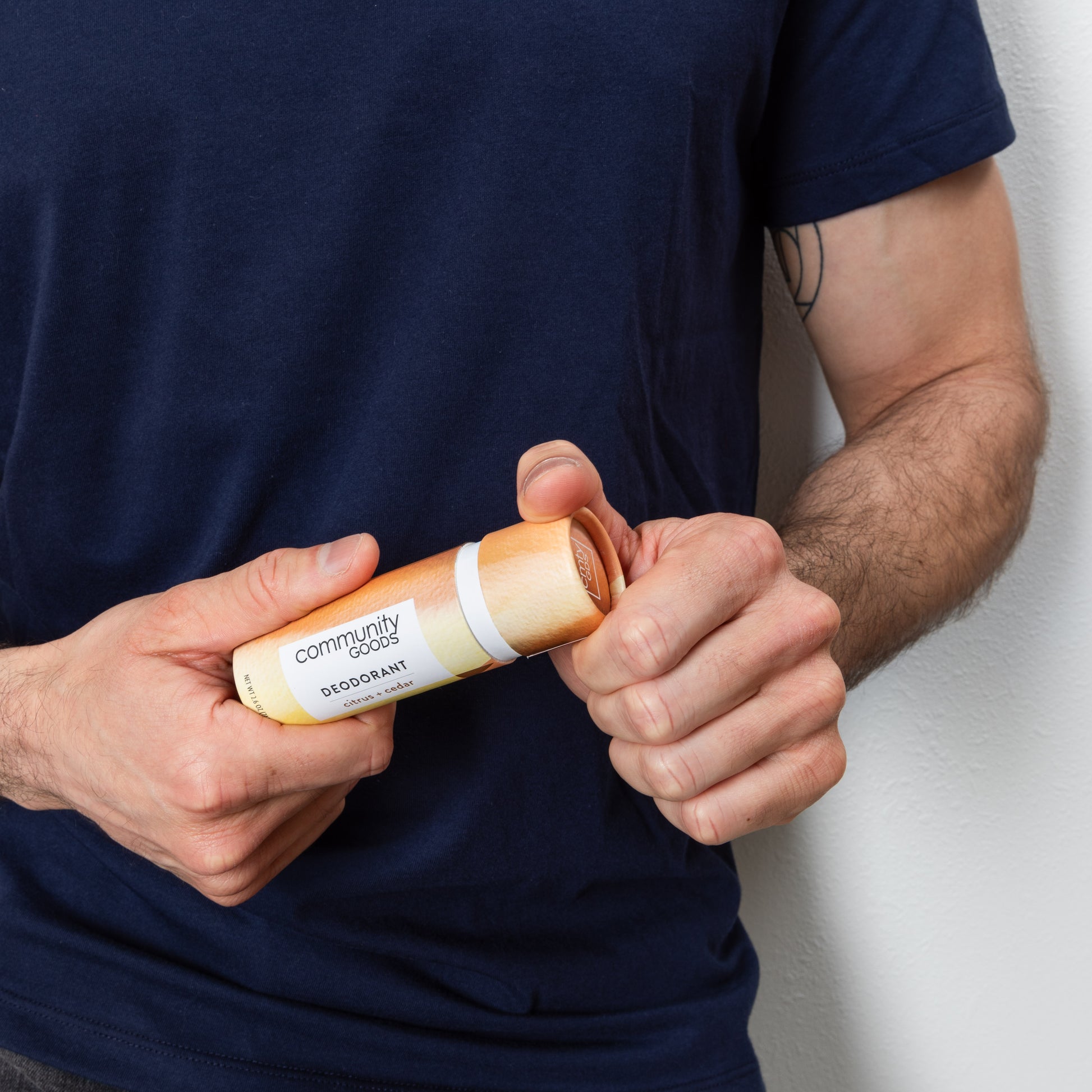 A man opens a natural deodorant, by Community Goods, in Citrus & Cedar scent.