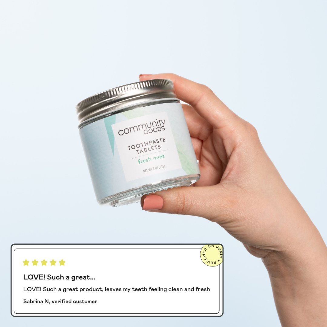 The best toothpaste tablets, by Community Goods. A glass jar being held by a woman's hand, next to a 5 star review.