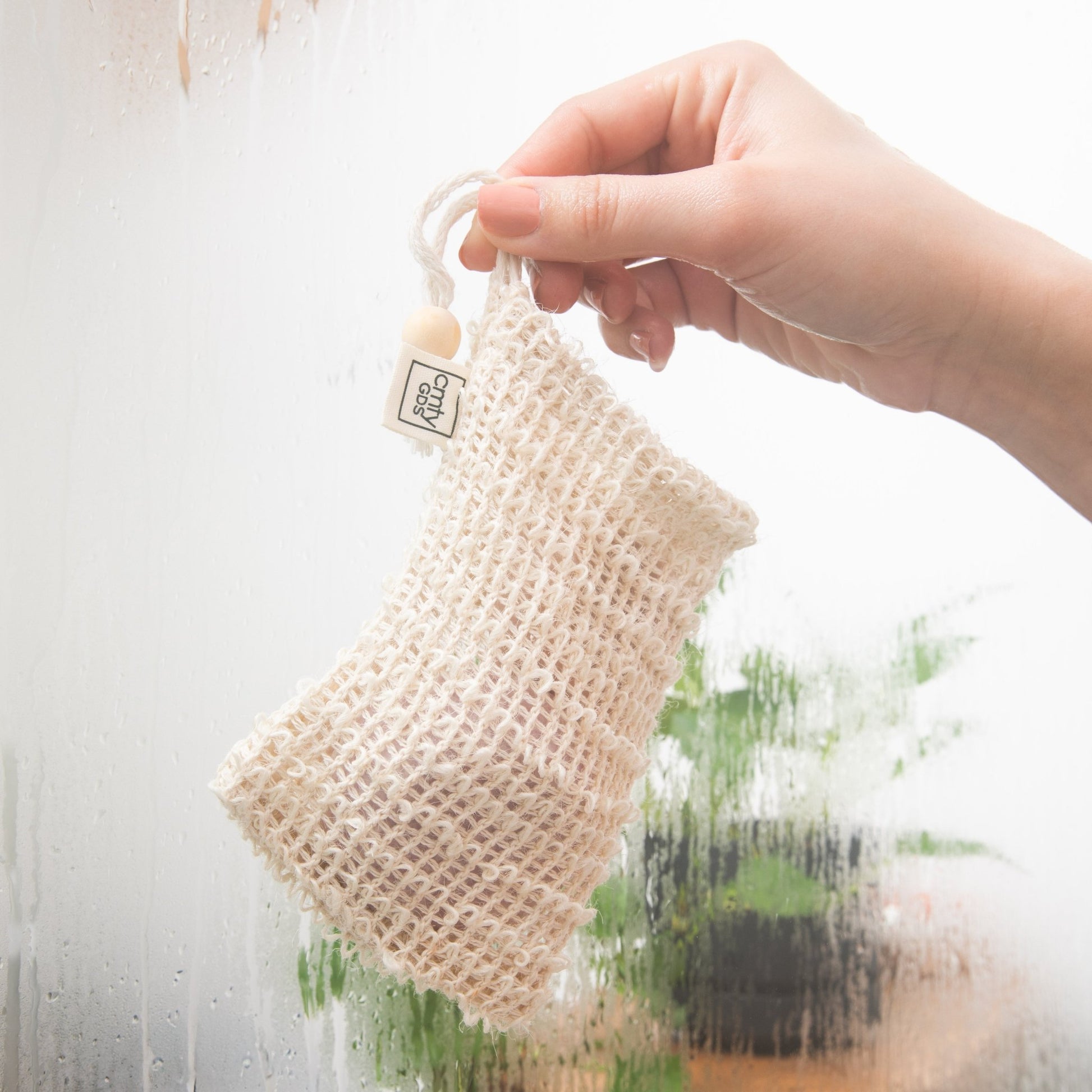 Sisal Shampoo Bar Saving Bag by Community Goods, being held in a wet shower.