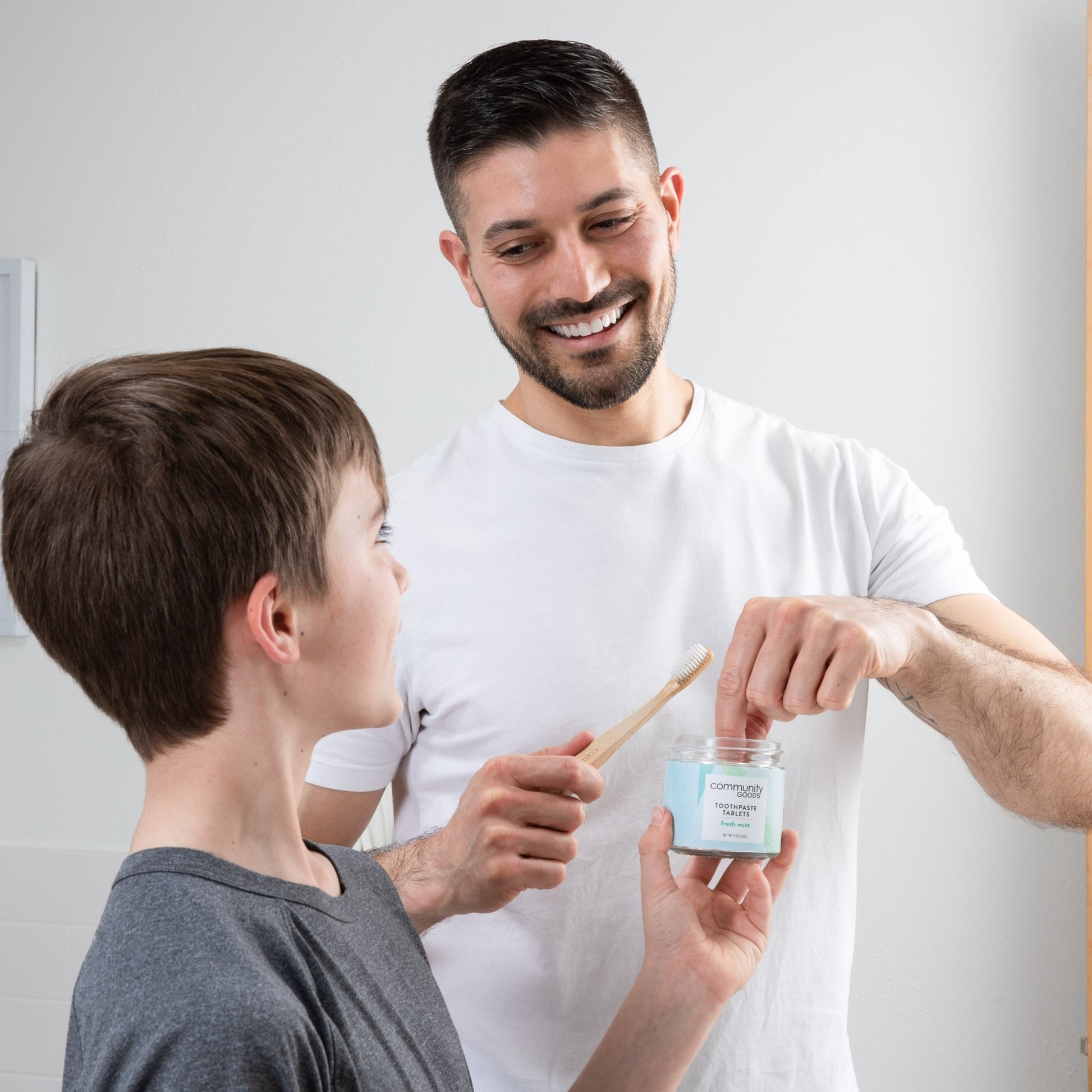 A father and son share the best toothpaste tablets while they brush with natural bamboo toothbrushes. 