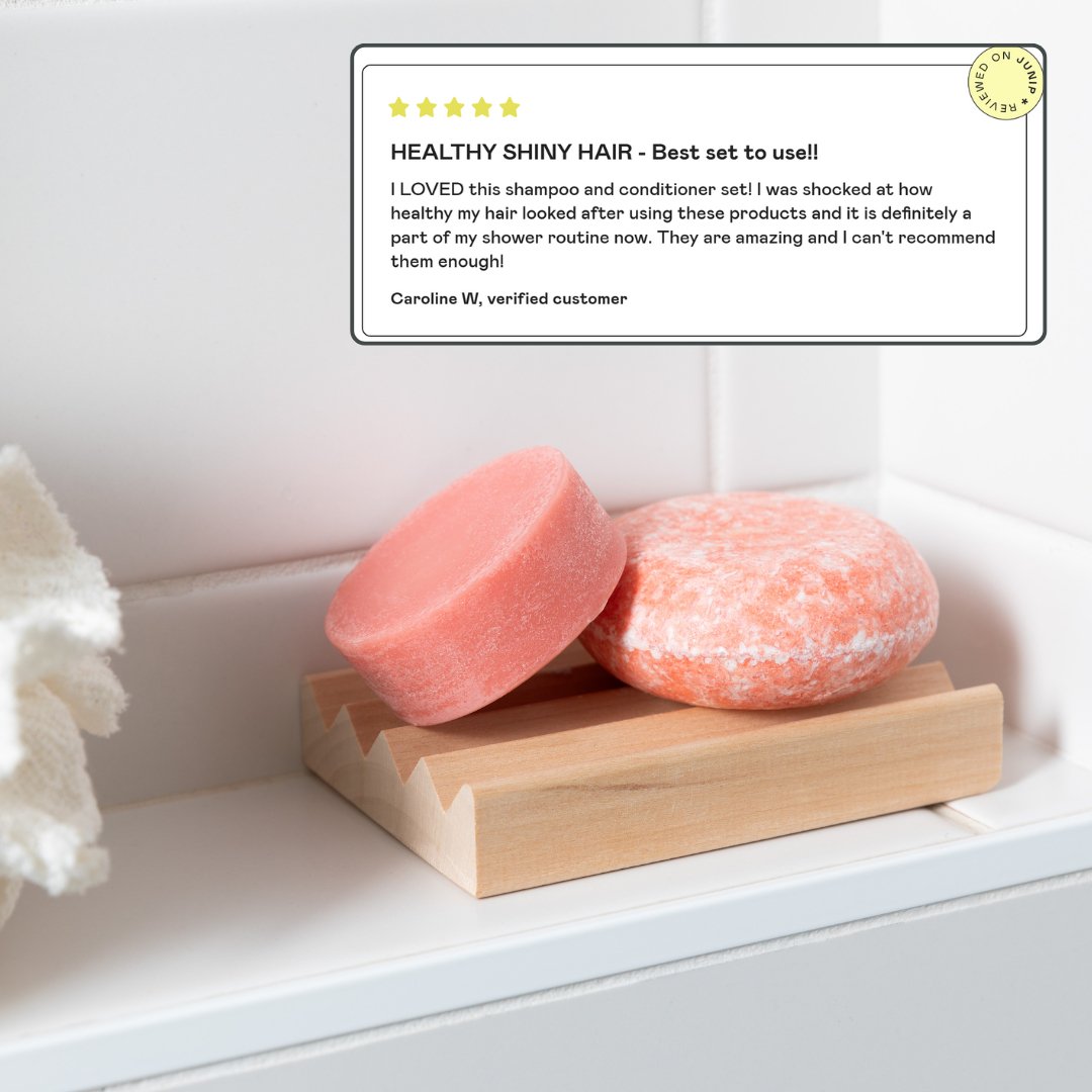 A natural Shampoo Bar and Conditioner Bar Set by Community Goods is shown in a modern bathroom next to a 5 star review saying it's the best set to use. 