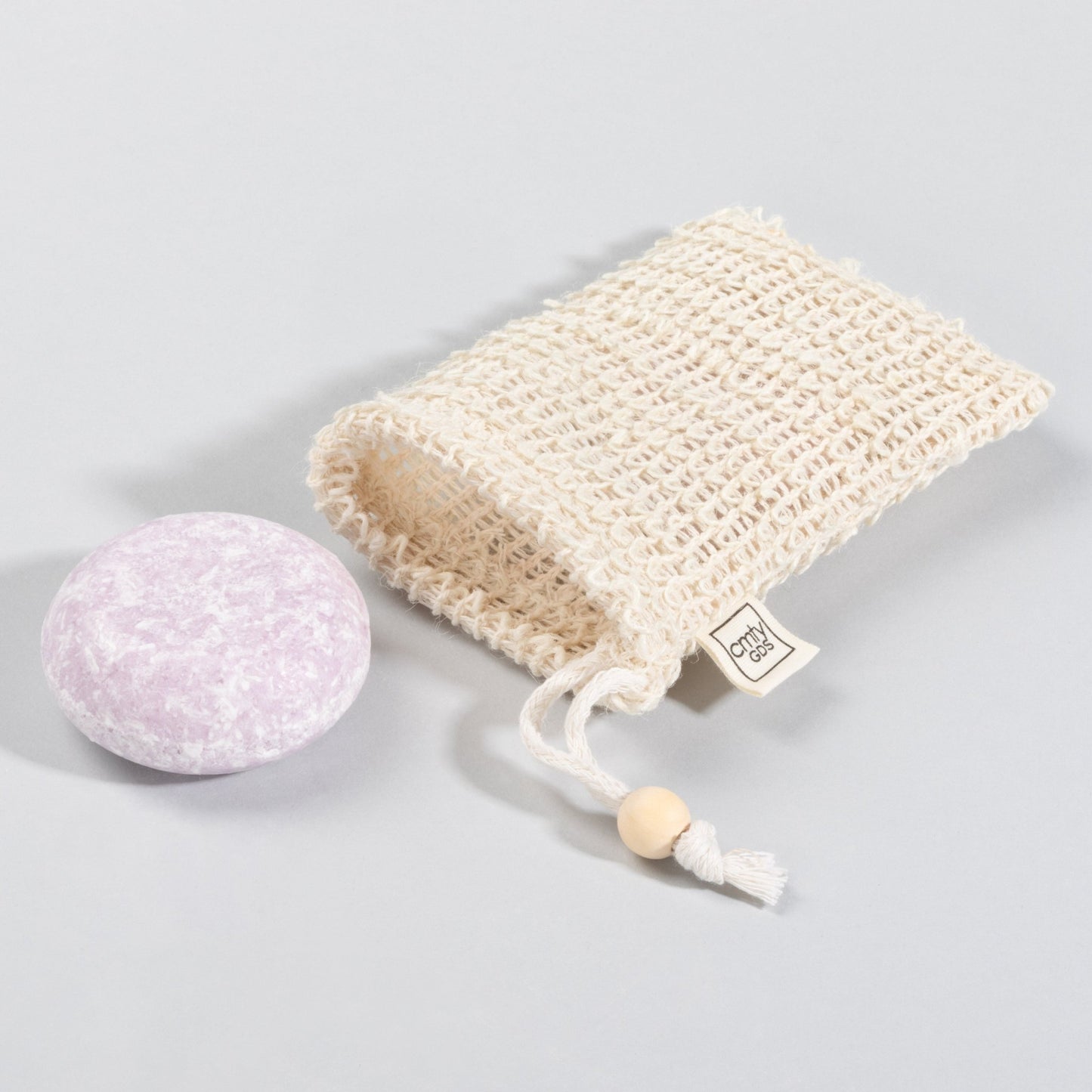 A lavender rosemary natural shampoo bar next to a sustainable sisal bag.