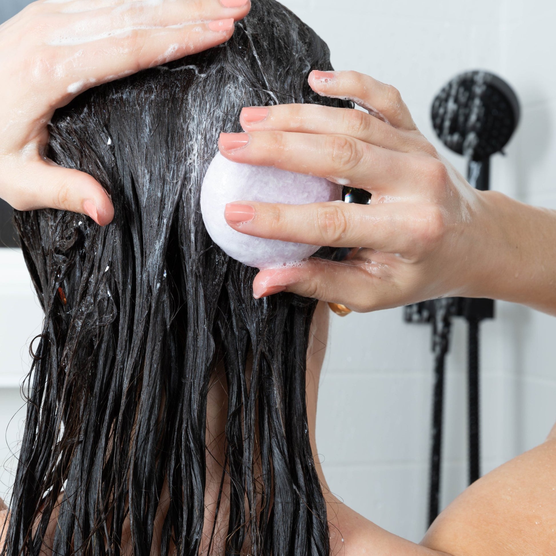 A woman washes her long hair with a pH balanced shampoo bar from Community Goods. The color safe bar is scented Lavender Rosemary. 